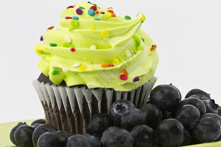 巧克力蛋糕加绿色的霜冻周围都是夏天的甜蓝莓糖结霜烘烤的甜图片