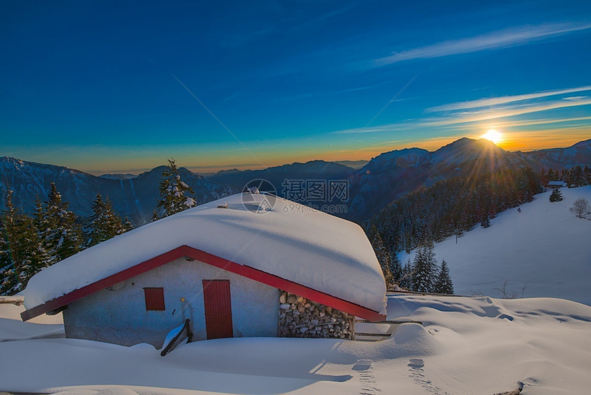 乡村的安静日落时雪下高山小屋全景图片
