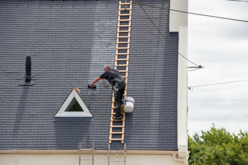 修理工作人在屋顶上用滚机传播产品男人图片