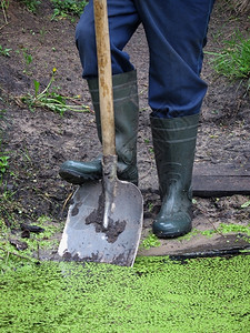 贴近一个用橡胶靴子铲挖池塘的人工具开机一种图片