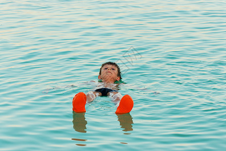 自然盐松弛男孩躺在死海的水面上图片