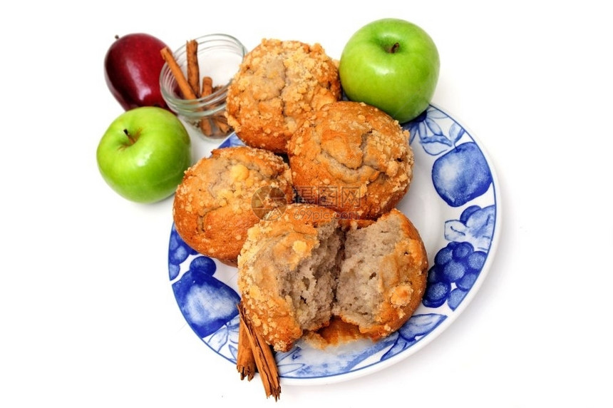 包子罐苹果和松香料早餐松饼以县风格的蓝色和白盘子上配有苹果和白背景孤立的肉桂香料配图片