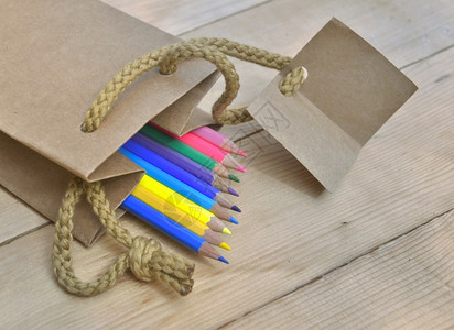 桌子纸袋中的彩色铅笔和木制桌上的标签蜡笔一种图片