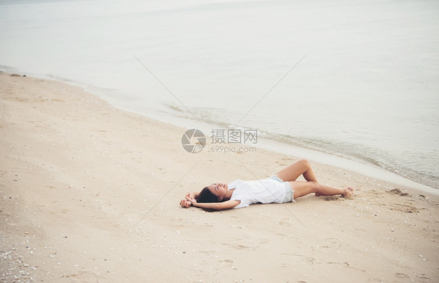 白色的旅行夏天穿着白色T恤衫的年轻女子躺在海滩上微笑着享受自然女生活方式概念的自然快乐图片