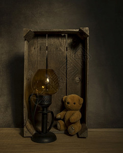 环境玩具木制的仍然活着老泰迪熊和金光在黑背景的桌子上一个旧木盒里图片