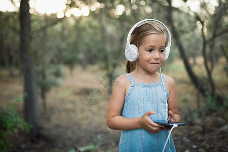 可爱的小朋友戴着耳机用手机听音乐图片