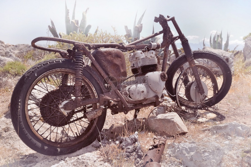 残骸的废旧老生锈自行车在岩石中的老弃垃圾摇滚图片