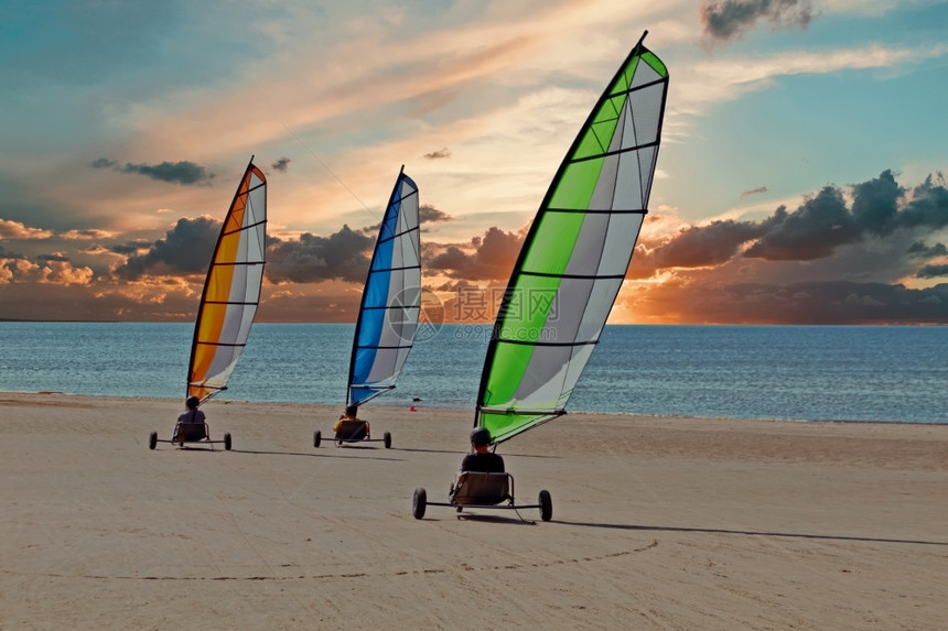 日落时在海滩上行驶的帆船马车图片