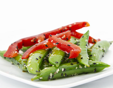 紧贴的糖炒豆沙拉被切成红胡椒和芝麻种子新鲜的豌豆红色图片