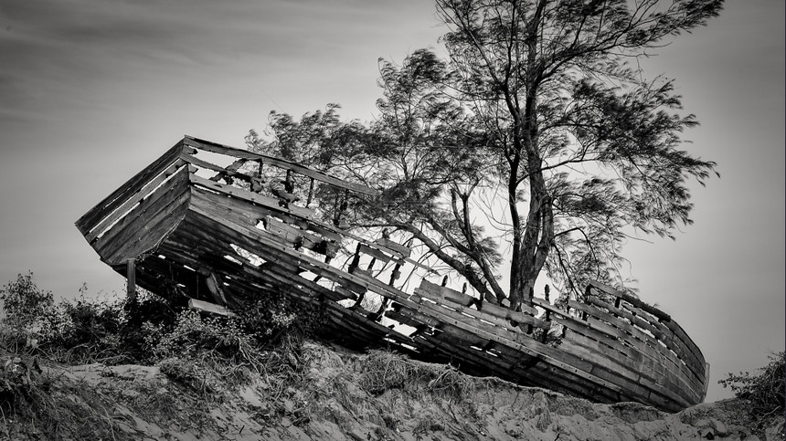 放弃岸上沉船一艘旧木冲上岸丢弃在马普托湾海滩的丘陵上图片