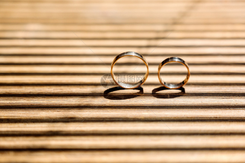 两只金婚戒指都放在棕色的木桌上图片