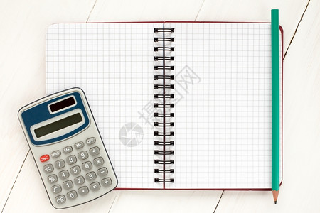 白色木制背景的电子计算器和螺旋笔记本机数学会计金融图片