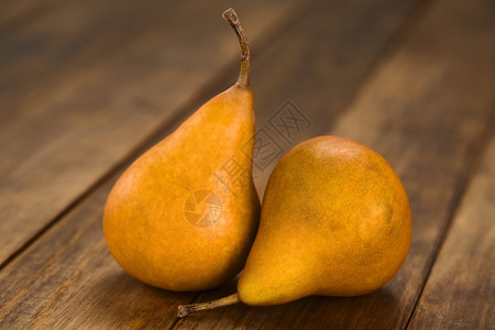 小吃黄色的两个成熟博斯克梨子在暗木上选取焦点聚于梨子前面食物图片