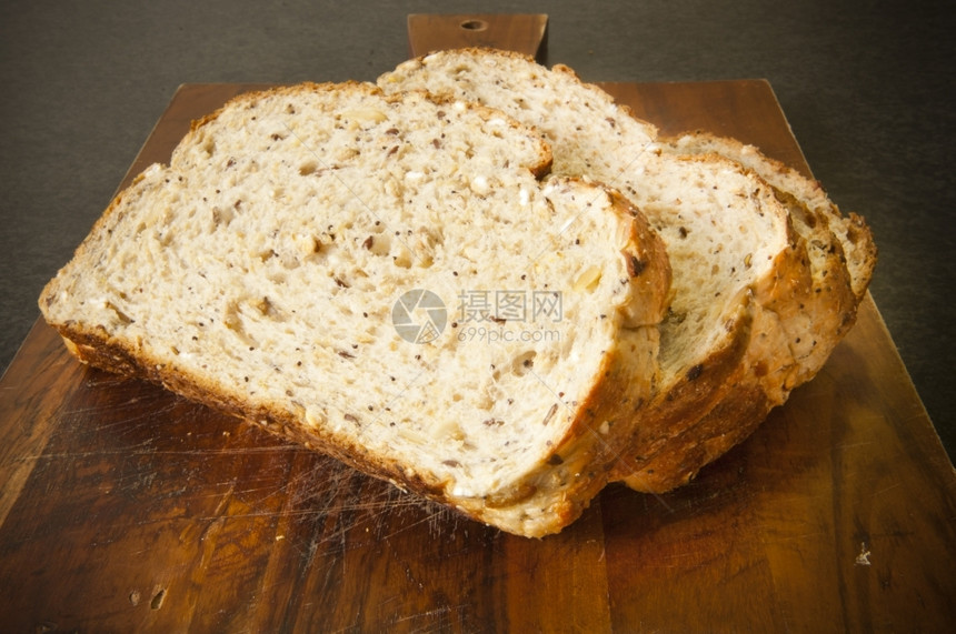 切片三明治木材面包板上带混合谷物的宽片面包块图片