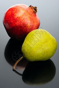 酒红色蔬菜石榴和黑背景的梨子有反射红色的图片