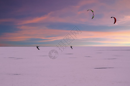 下雪的冬季黄昏时在荷兰乡间冷冻湖上漂浮的Kite冲浪者冬天日落图片