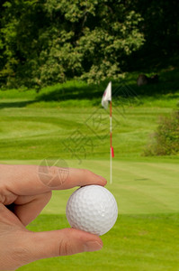 手持高尔夫球绿色高尔夫带旗在背景中游戏玩旗帜图片