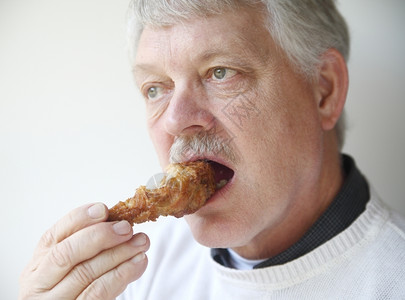 老年男子咬炸鸡肉腿水平的营养图片