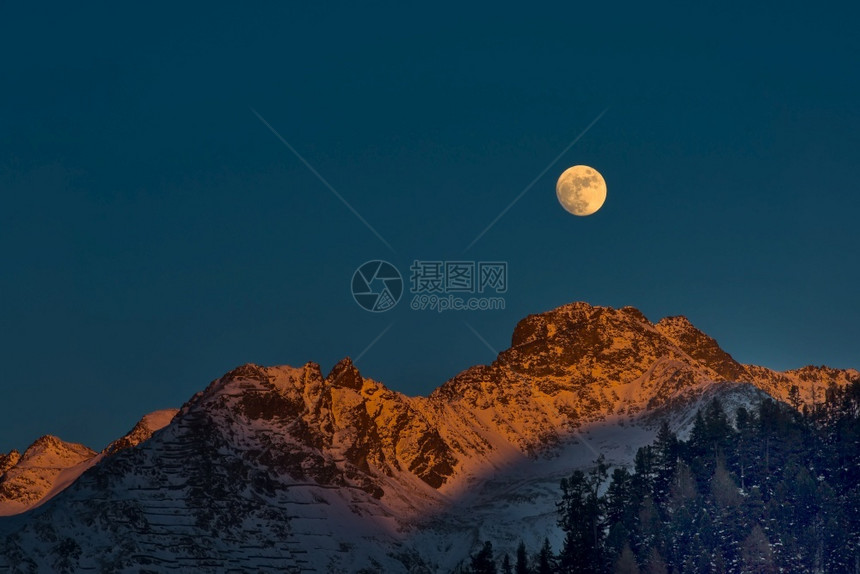 天空日落时满月的冬山图片