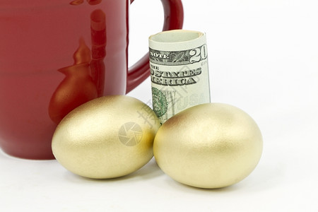 商业二金巢蛋放在美元货币和红咖啡杯的面前金子钱图片