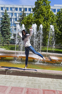 在喷泉背景上跳跃的高加索黑发女人头天空白色的图片