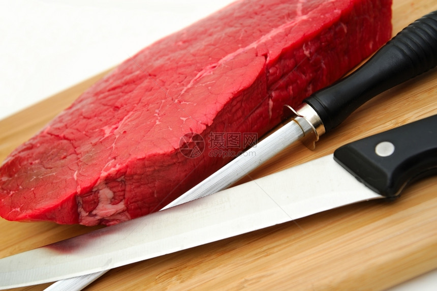 本迪克森RawSteakAnKnife一大块未煮熟的牛排用屠宰刀和白底磨在切肉板上屠夫一种图片