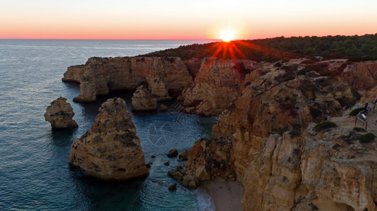 海浪结石环境日落时从葡萄牙阿尔加维的PraiadaMarinha图片