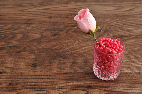 粉色的圆形装满粉红色珠子的玻璃杯里人工玫瑰质地图片