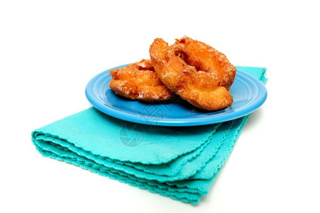 一种食物棕色的两块鲜奶油甜圈放在绿松石酱上用浅彩背景的餐巾纸图片