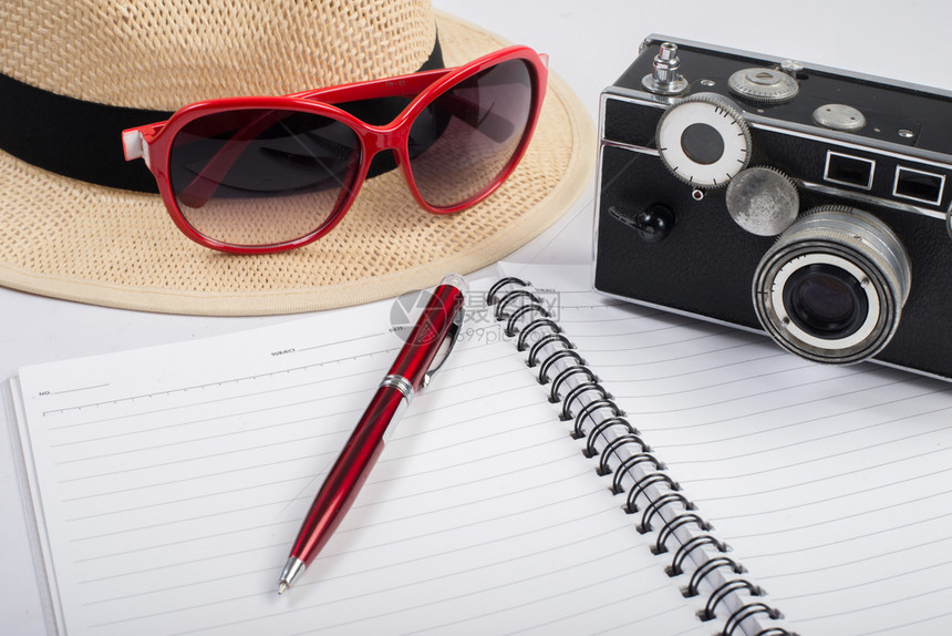 帽子太阳眼镜和古代照相机用笔记本隔绝在一顶帽子太阳眼镜和古代相机上用笔记本隔绝在白色背景上太阳镜时尚一种图片