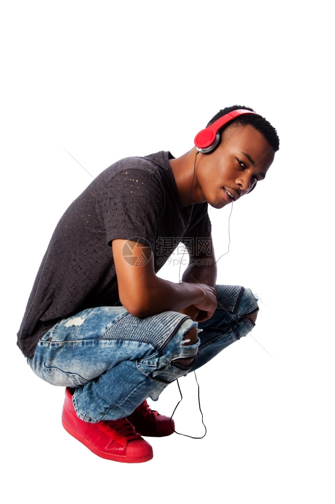 青春期非洲英俊的青少年在蹲着时听穿戴红色耳机的音乐男生牛仔裤图片