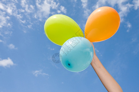 天空背景上带有颜色气球的手飞空喜庆图片