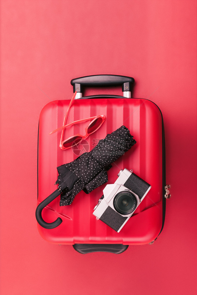 红色的旅行手提箱红色墨镜旧照相机红背景黑色雨伞和红墨镜离开老的图片