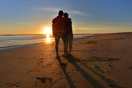 女士一对紧的情侣背影看着海滩上美丽的日落太阳人们图片