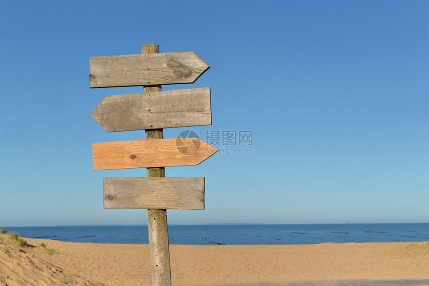 蓝色天空下沙滩上一个柱子的木头标志蓝色空邮政图片