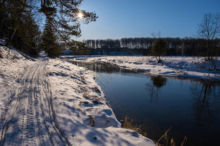 初晴冬日霜明亮的冬日阳光和寒雪海岸的一条小河以及片无云的蓝色天空下雪晴背景