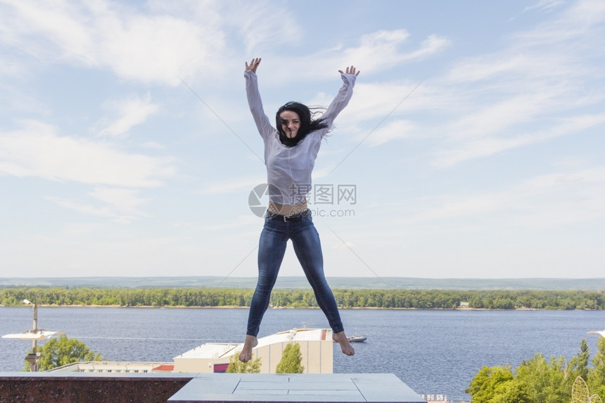 河水背景上年轻女跳跃的照片白色天空淑女图片