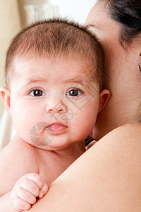 新生可爱的唾液衣着婴儿的拉丁裔母亲眼睛眨流口水的婴儿脸图片