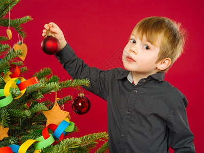 一种快乐的位男孩在圣诞树上挂着装饰物的照片假期图片