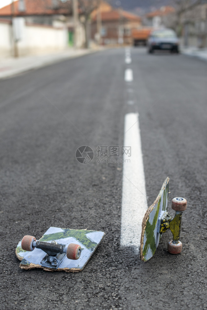 极端受伤孩子黑色沥青街上的断板滑白色街道线图片