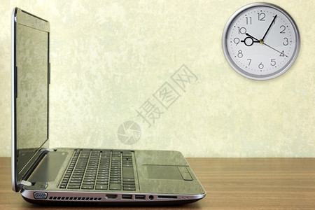 一种时间桌上的笔记本电脑和墙上的时钟工作图片