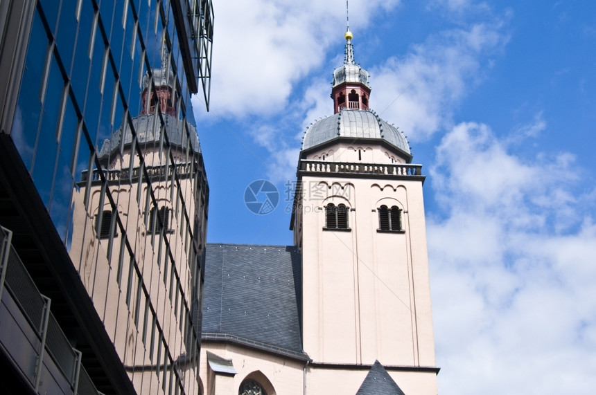 老的德国圣玛丽亚希姆尔法赫特教堂及其在古龙水中现代建筑的反映图片