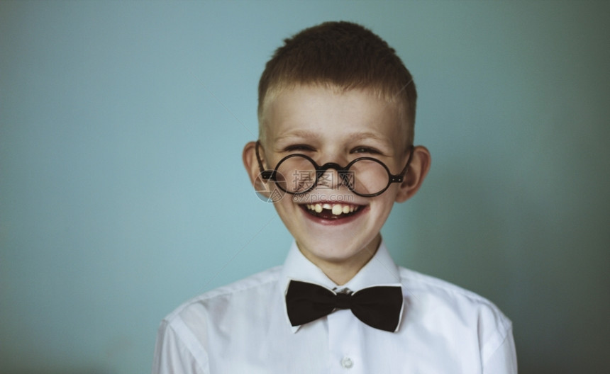 一个戴眼镜和黑色弓领带的年轻无牙男孩一种年轻的头发图片