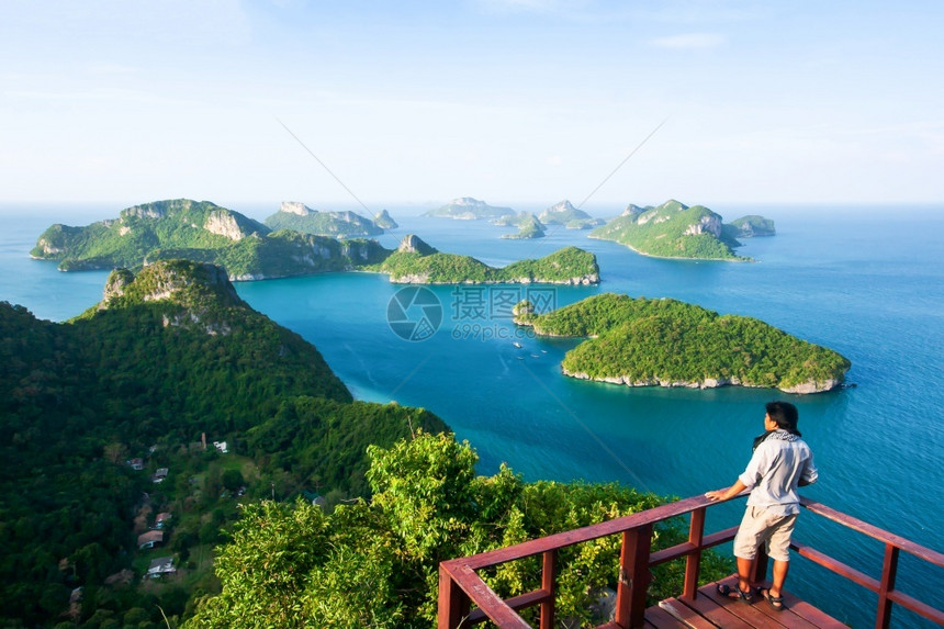 一位青年男子身旁随便独自站在KohWuaTaLap的顶端观望同时享受着与许多热带岛屿相伴的蓝色海景美阳光灿烂的夏日风景蓝色的尽管图片
