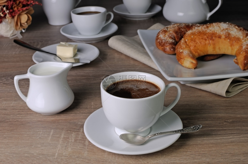 杯子牛角包咖啡桌上加牛角面包奶油和食物图片