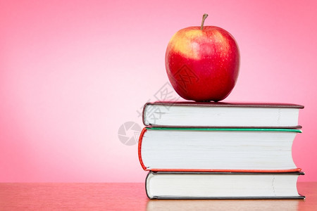 有粉红色背景的书上红苹果学校教科书食物图片