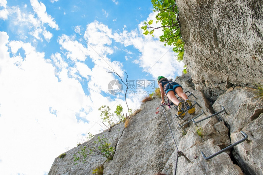 年轻女孩爬上梯子登攀岩的石运动登山者首脑图片