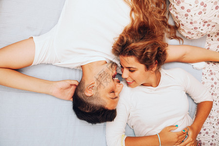 男人年轻笑着的异恋情侣躺在床上友谊女朋图片