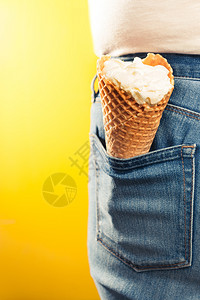 颜色食物黄背景的牛仔裤口袋中冰淇淋甜筒奶油图片