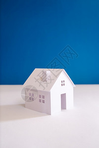 财产林极简主义者所有的白色纸迷你房屋有蓝色背景图片